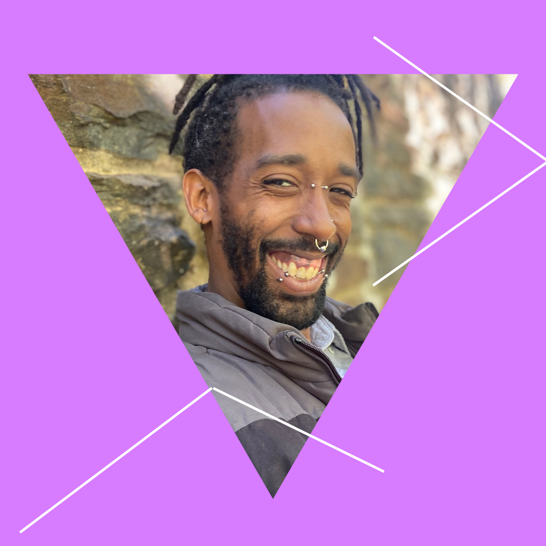 A triangle shape image of Talbolt Johnson grins widely. He has medium brown skin, facial piercings and a beard. White intersecting lines bisect the image